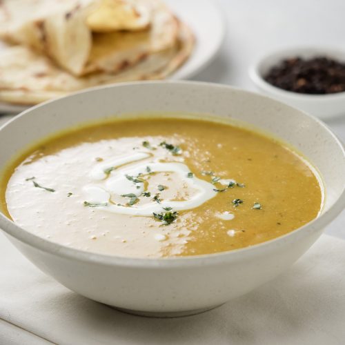 Mulligatawny soup in a white bowl from the front.