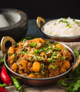 Restaurant style aloo keema in an Indian style hammered copper serving dish.