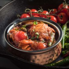 Nearly restaurant chicken jalfrezi in an Indian copper bowl - front view.