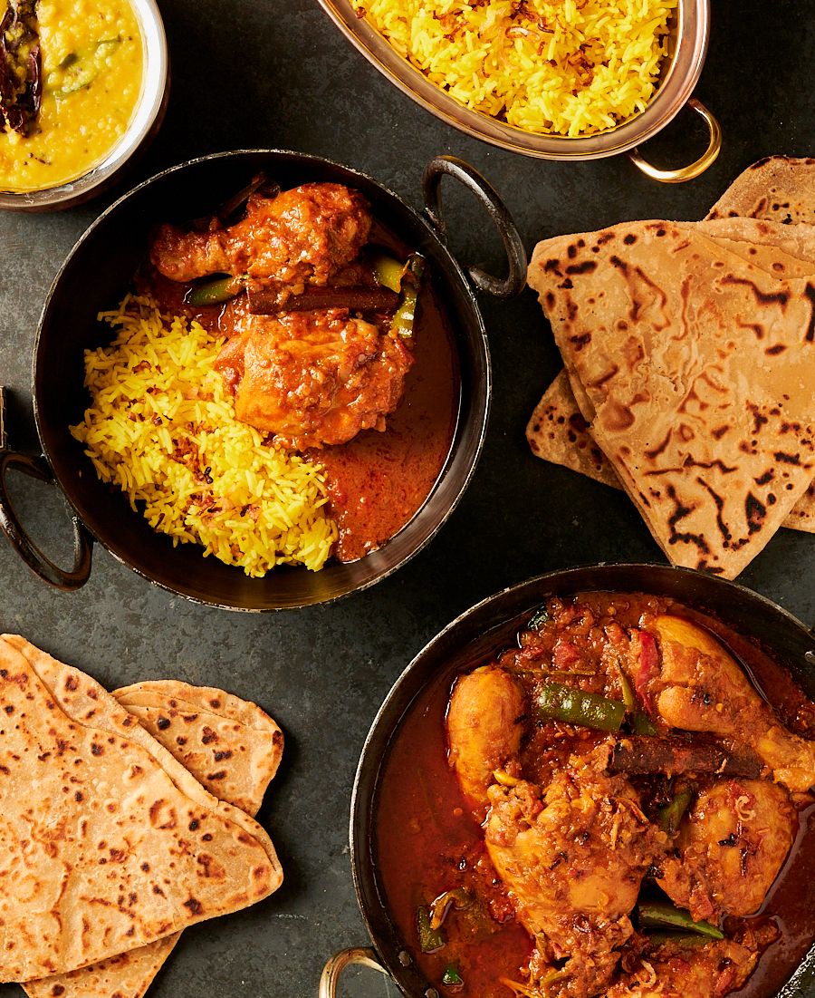 Table scene from above - chicken curry, dal, rice and parathas