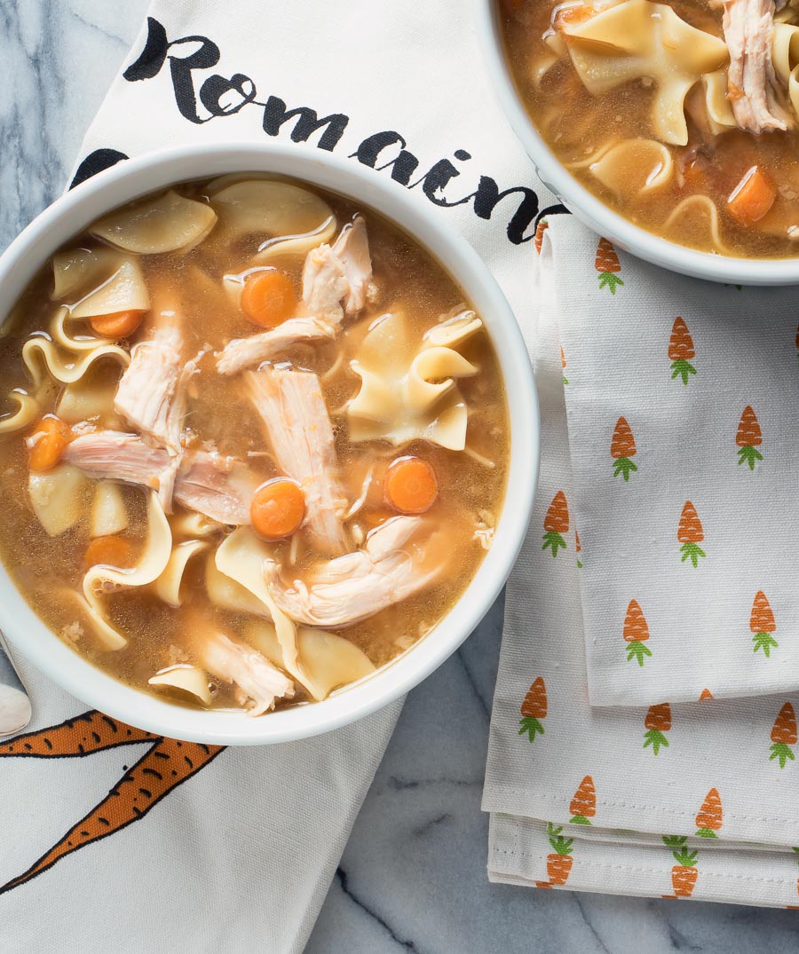 Turkey noodle soup with carrots in a white bowl.