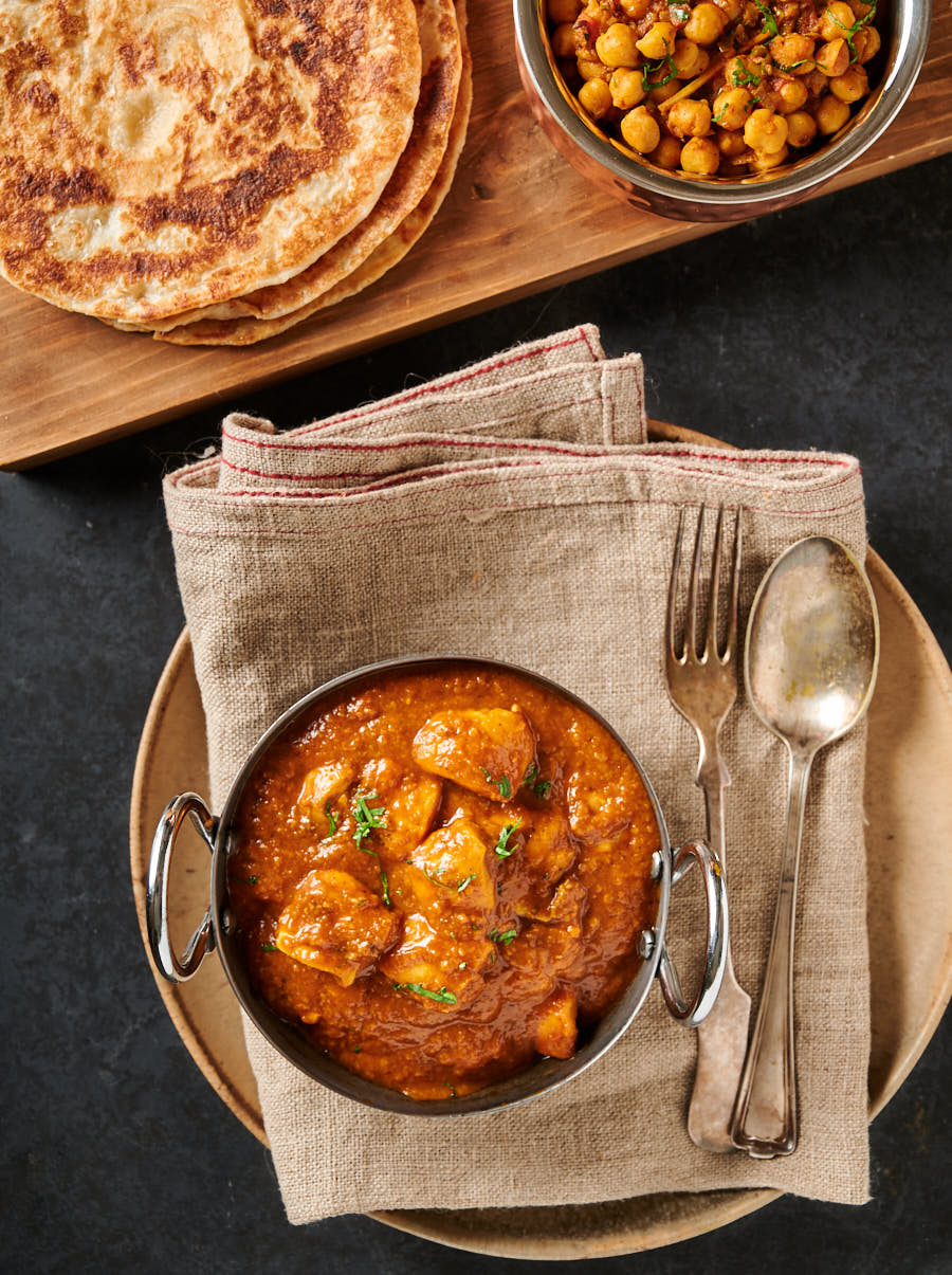 Indian restaurant dhansak curry, chana masala and flat bread table scene from above.