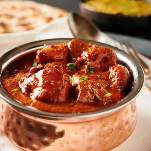 Chicken tikka masala in an Indian copper bowl from the front.