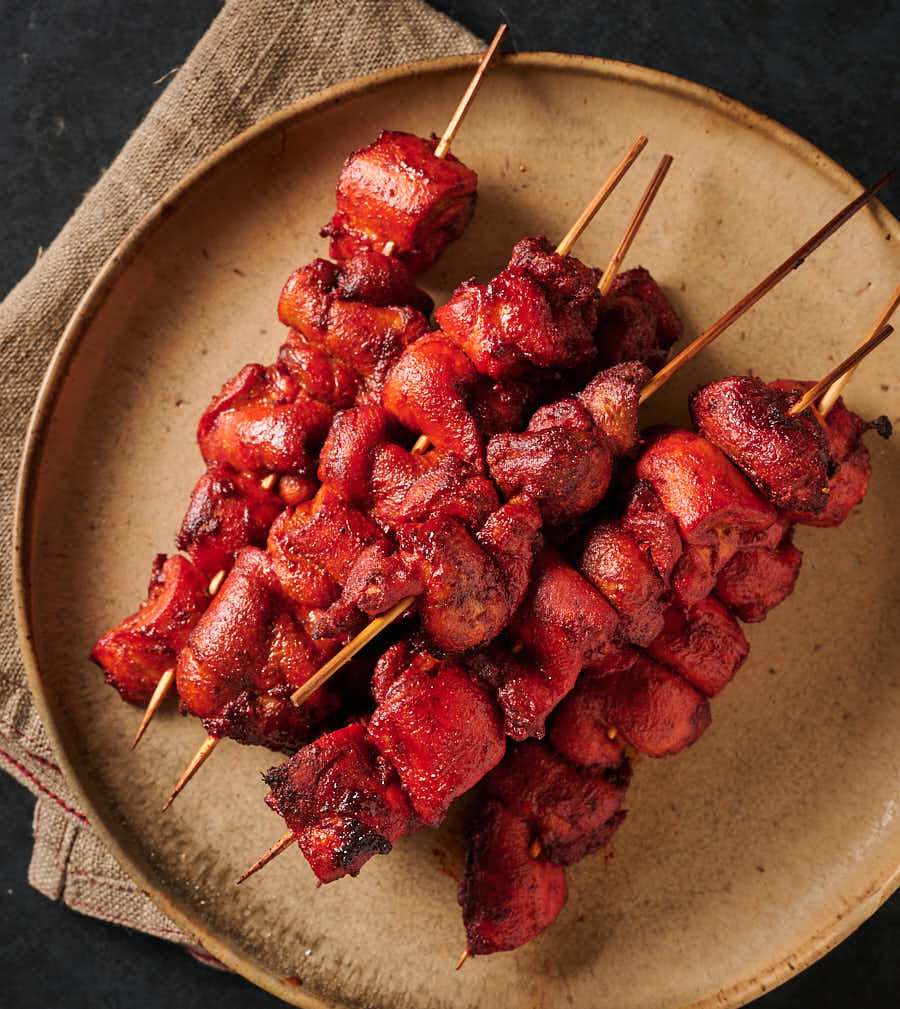 Skewers of chicken tikka kebab on a plate from above.