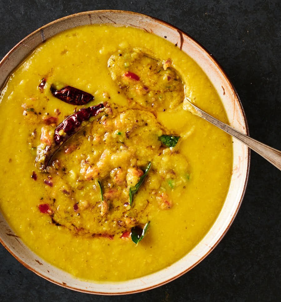 Mixing bowl of tarka dal with tarka mixed in partially from above.
