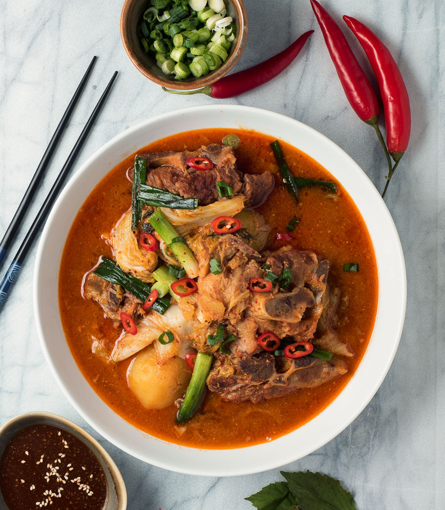 Korean pork bone soup with red spicy broth in white bowl from above.