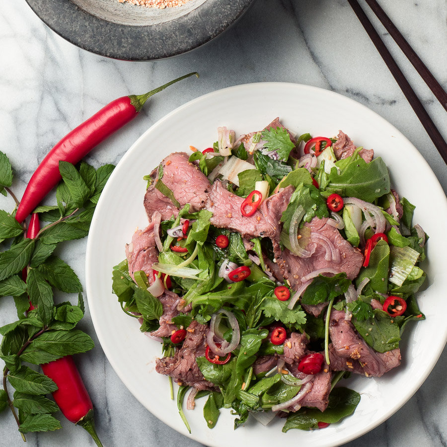 Overhead view of spicy Thai beef salad garnished with red chili slices.