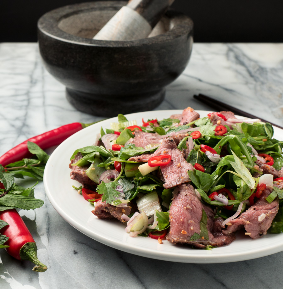 spicy thai beef salad on a white plate garnished with red chili front