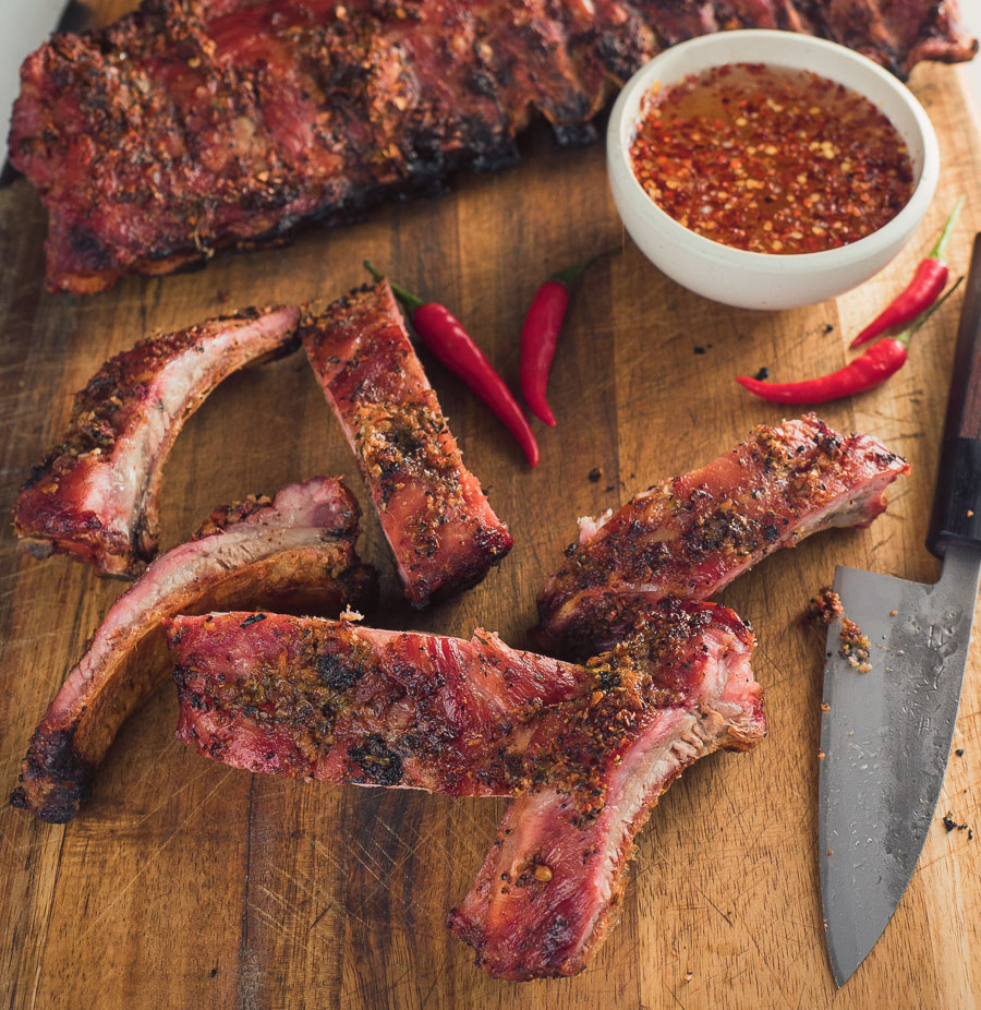 Thai ribs on a cutting board with bowl of dipping sauce