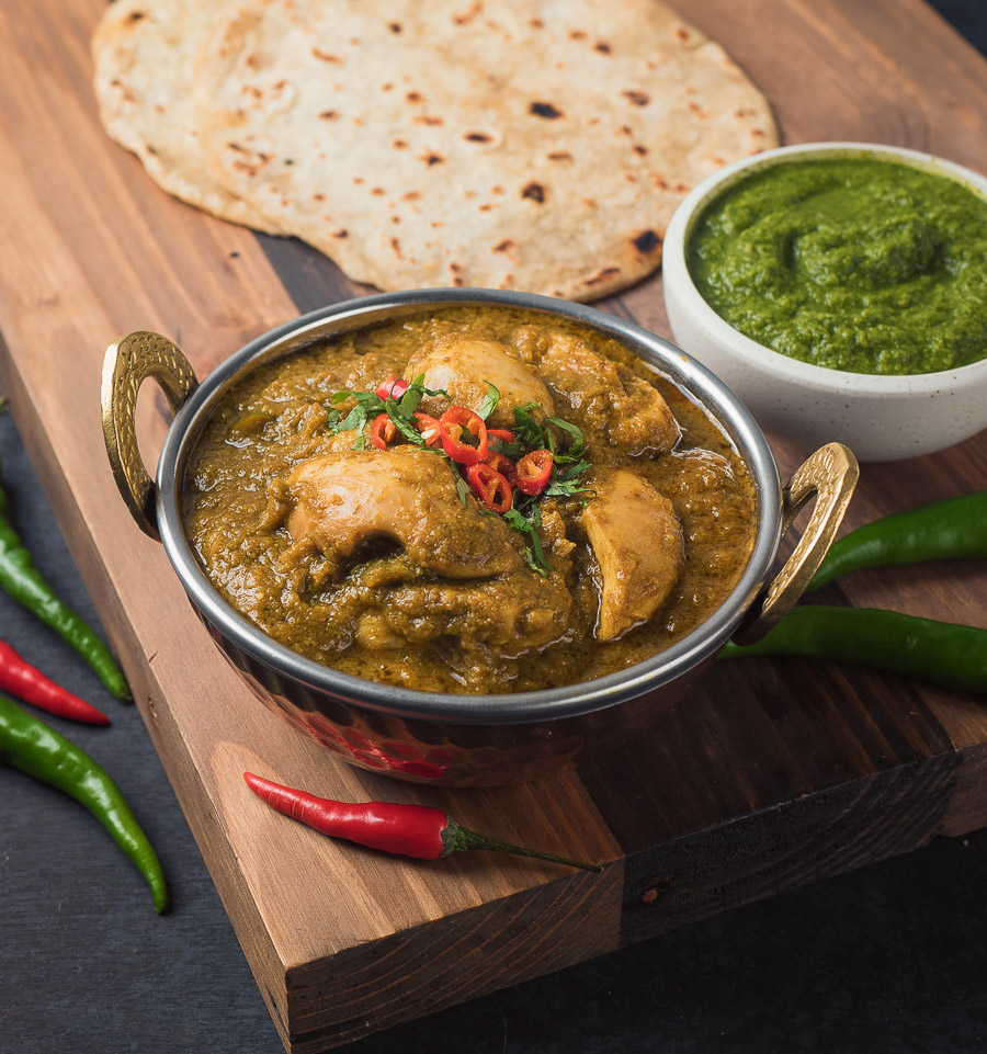 hariyali chicken curry in Indian copper bowl with mint coriander chutney.