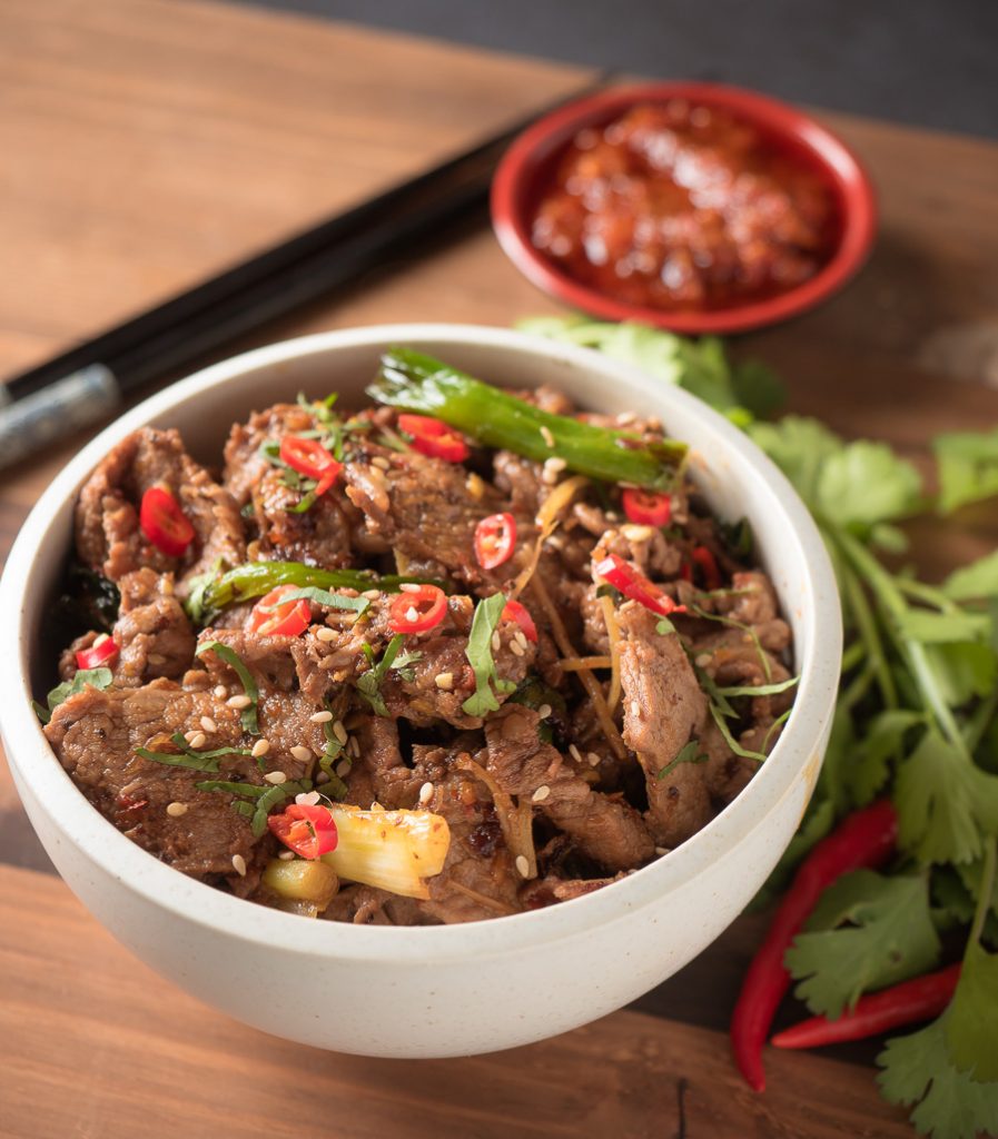 ginger beef stir fry in a white bowl close up