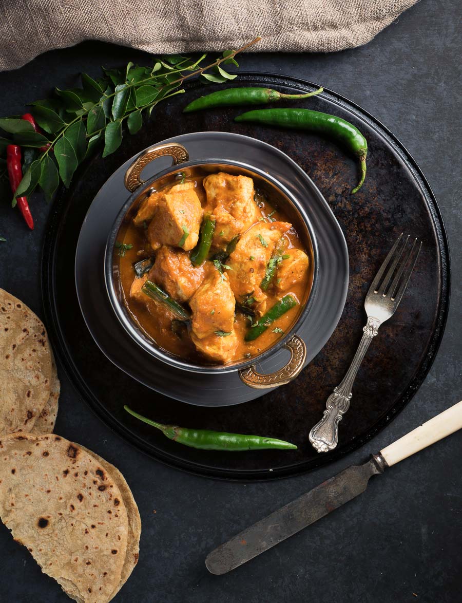 Chettinad chicken curry with chapati and chili garnish.