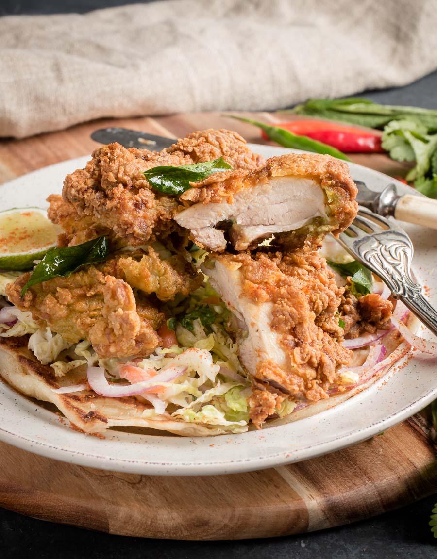 Crispy Kerala fried chicken cut with knife and fork.
