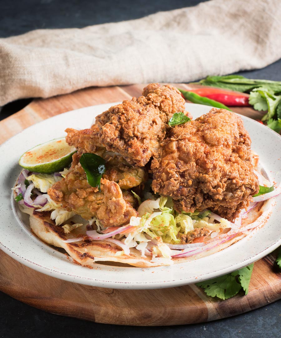 Crispy Kerala fried chicken on slaw from the front.