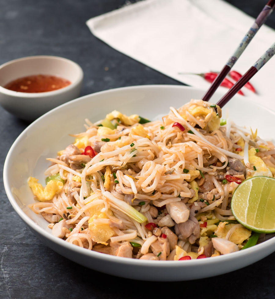 Chicken pad thai with chopsticks sticking up.