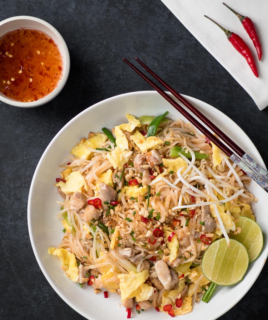 Chicken pad thai in a white bowl from above.