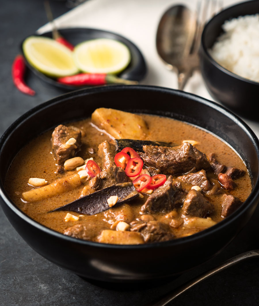 Close-up of beef massaman curry in a black bowl.