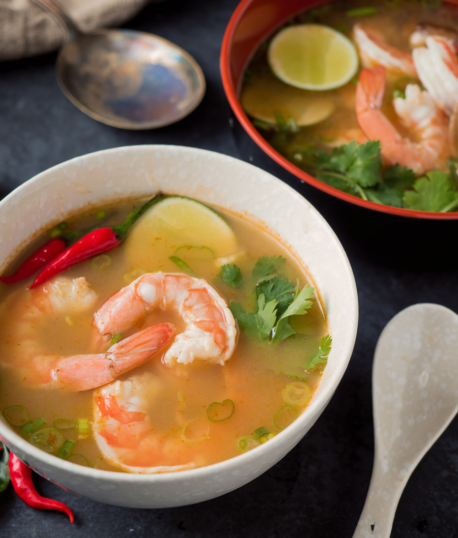 Tom yum soup in a white bowl up close.