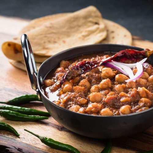 Punjabi chole masala in an Indian iron dish from the front.