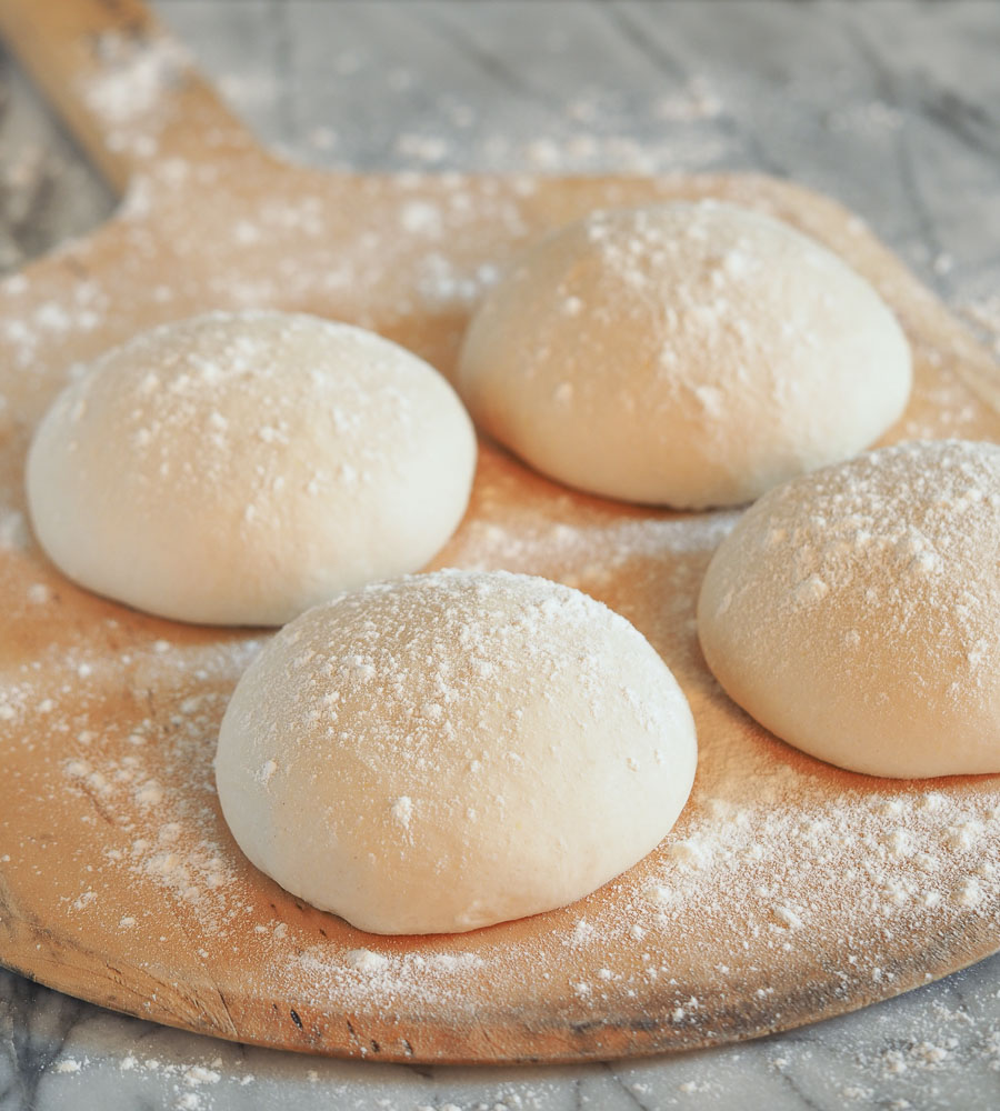 Balls of Neapolitan pizza dough dusted with flour.