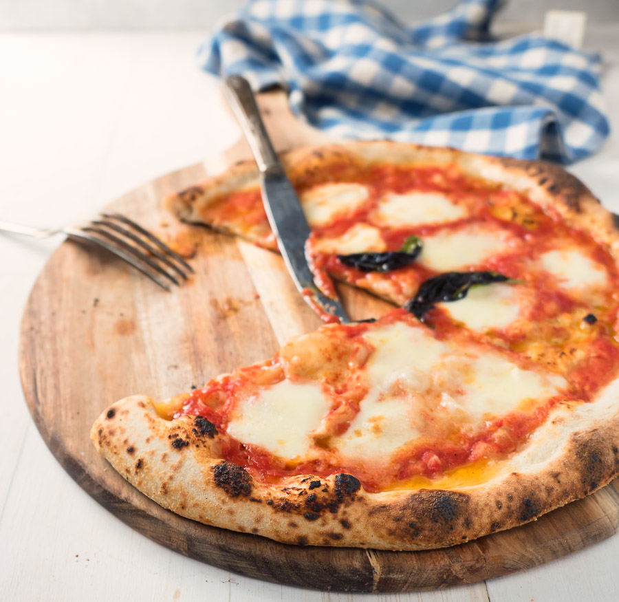 Partially eaten pizza margherita with knife and fork.