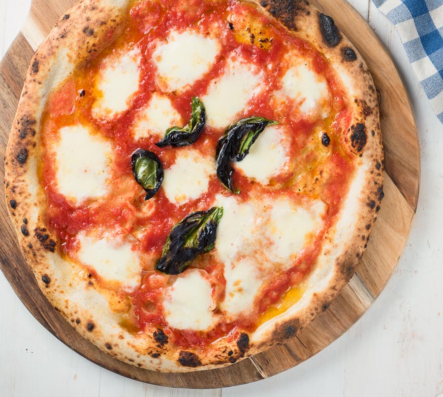 Pizza margherita on a cutting board from above.