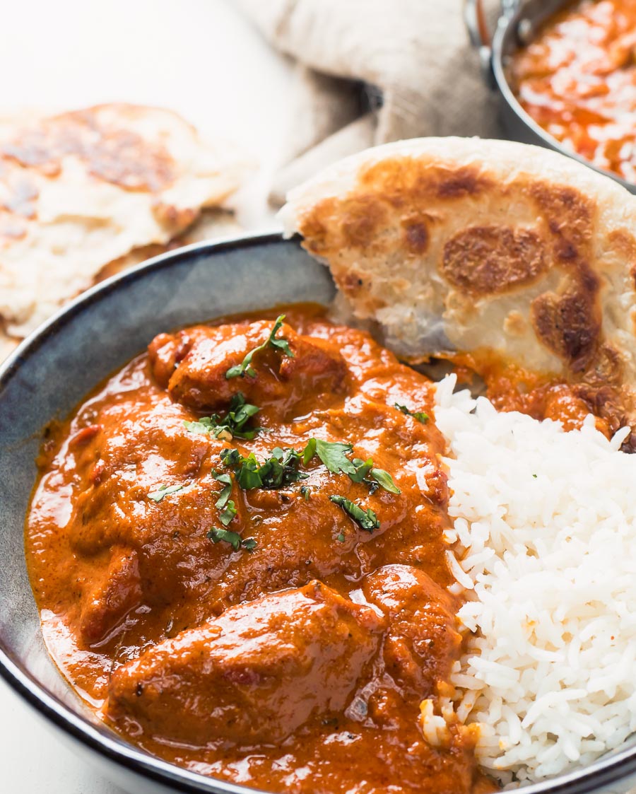 Restaurant butter chicken in a bowl with rice and paratha