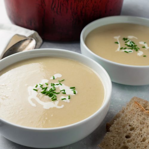 Two bowls of potato leek soup garnished with cream and chives.
