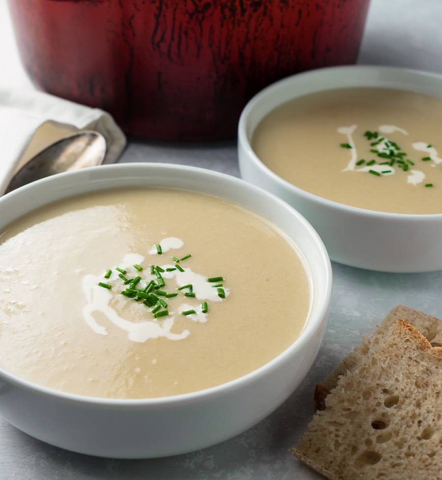 Two bowls of potato leek soup garnished with cream and chives.