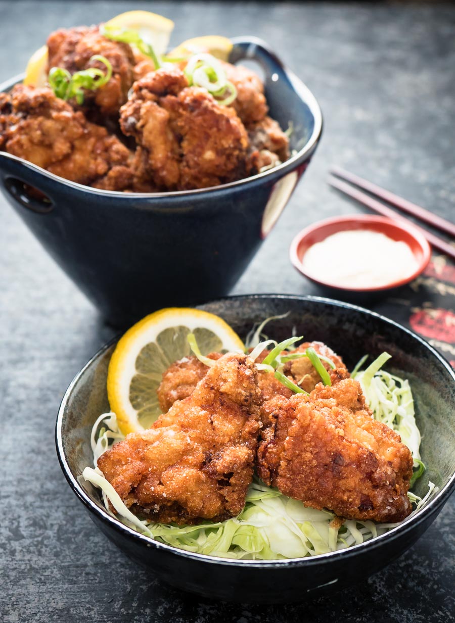 Plate with karaage chicken on a bed of julienned cabbage.