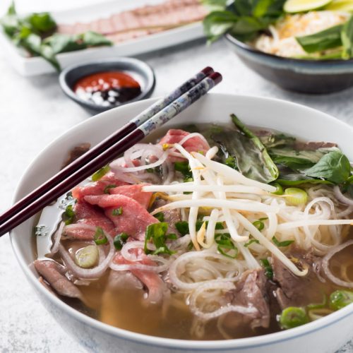 Bowl of beef pho with chopsticks from the front.