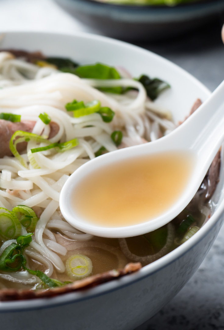 Beef pho broth in asian spoon