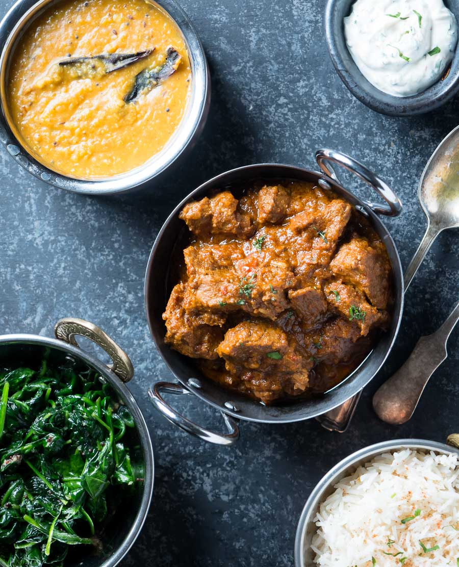 Laal maas surrounded by lentils, rice and spinach.