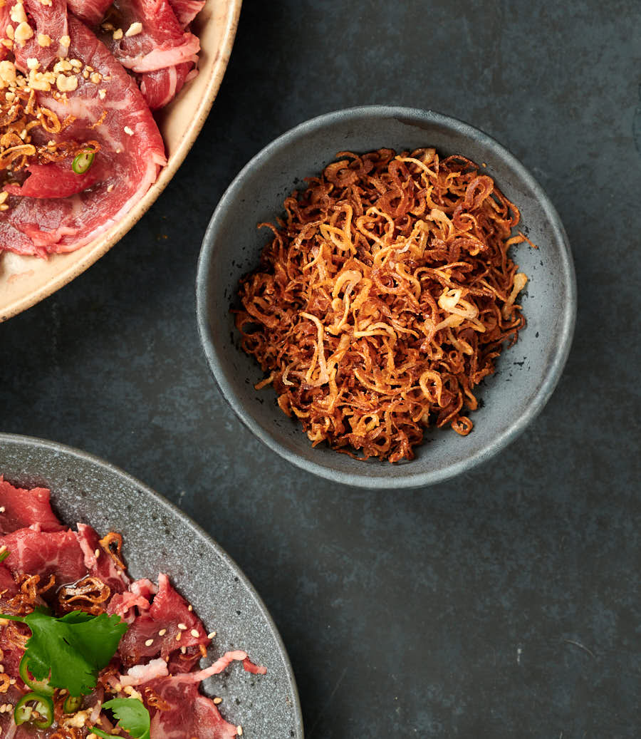 Crunchy brown fried shallots in a bowl from above.