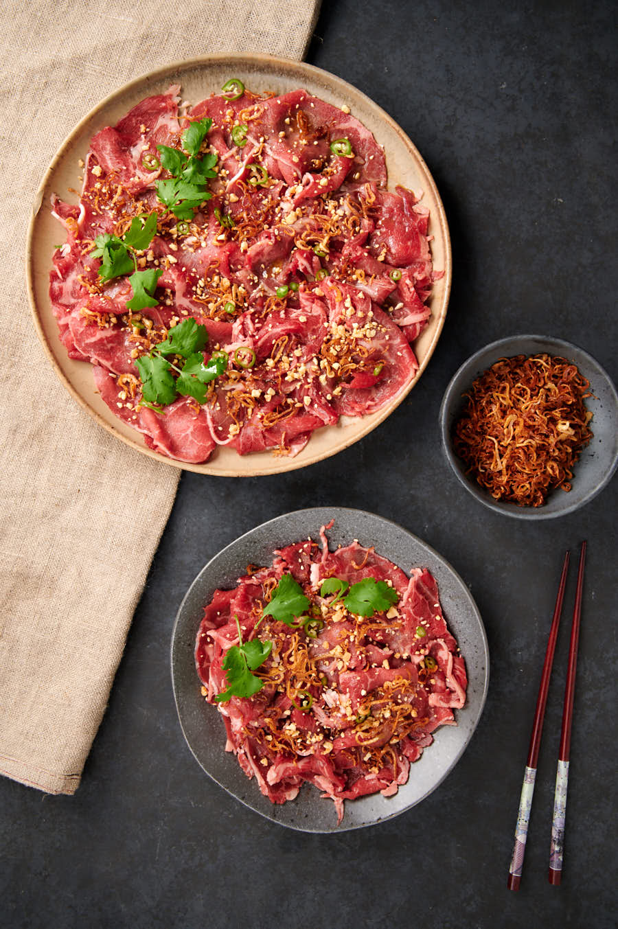 Plate and platter of Asian style carpaccio from above.