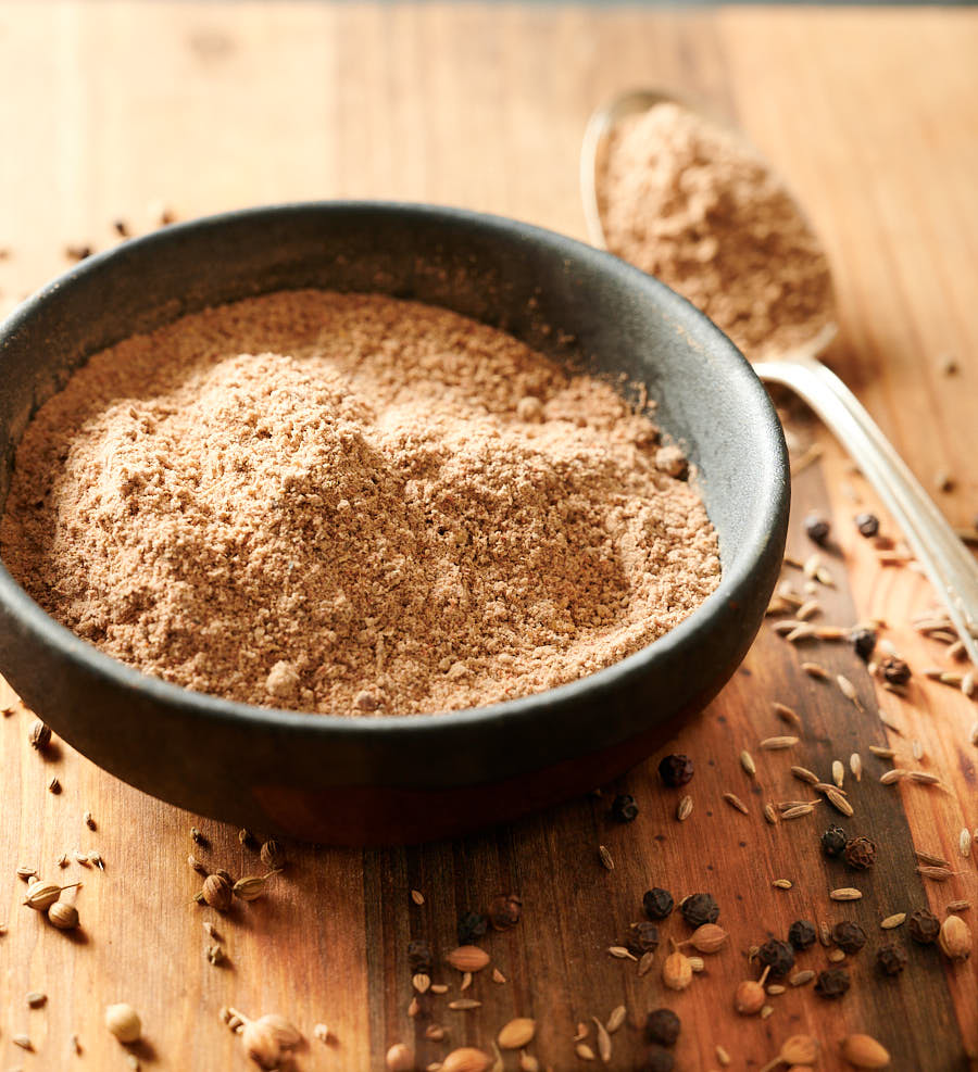 Chaat masala spice mix in a dark bowl from the front.