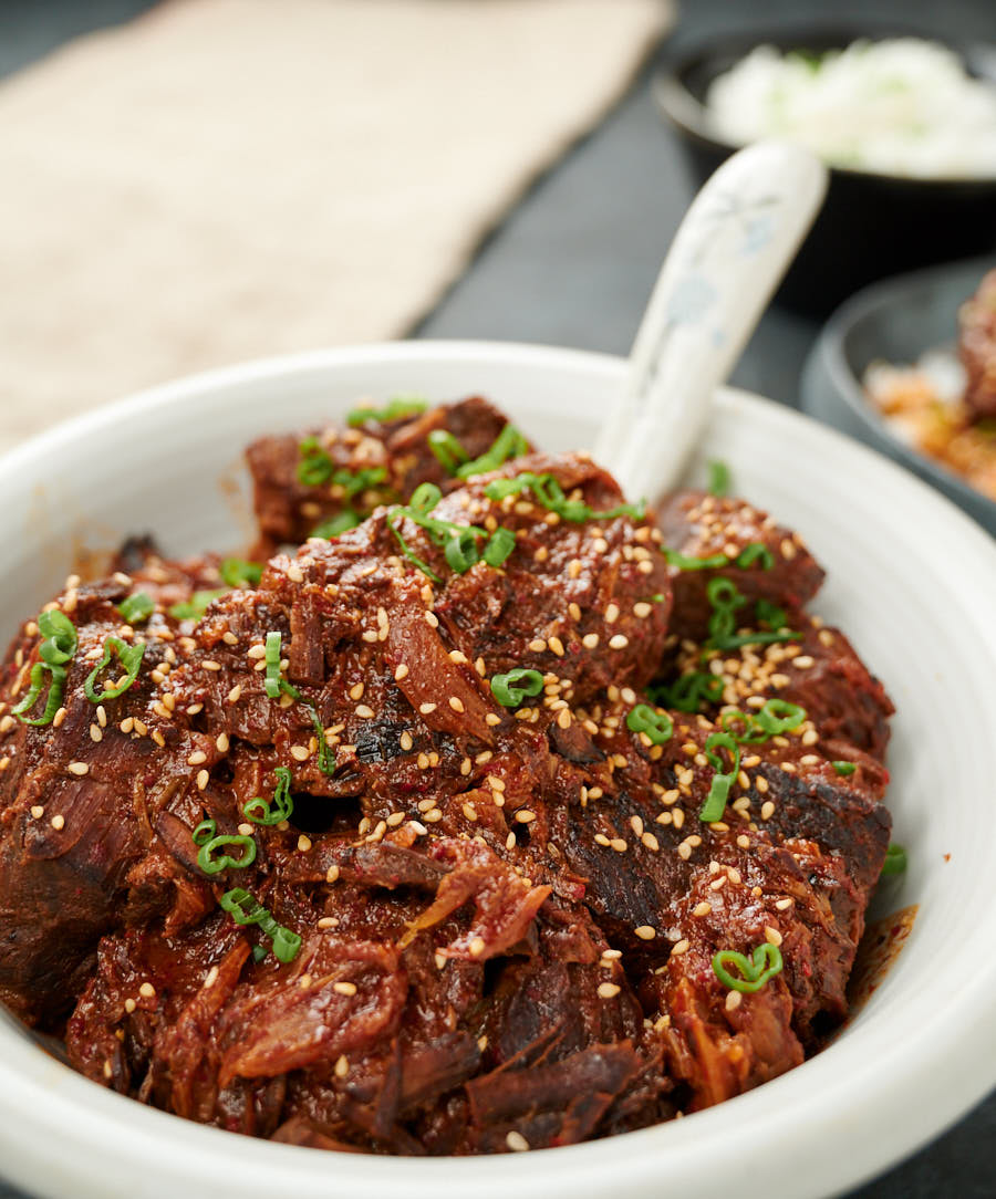 Korean beef stew in a serving bowl with Asian spoon from the front.