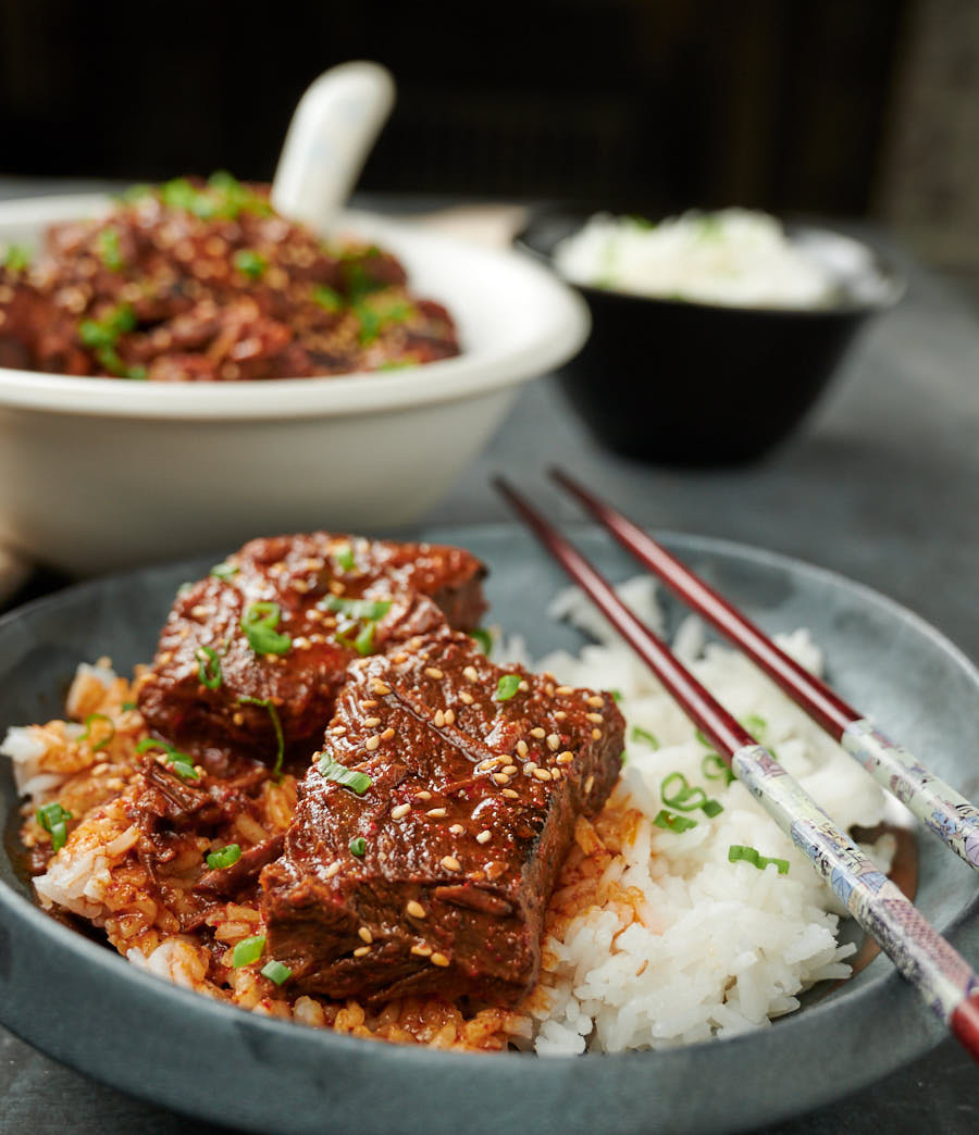 Korean beef stew with rice on a dark plate with chopsticks.