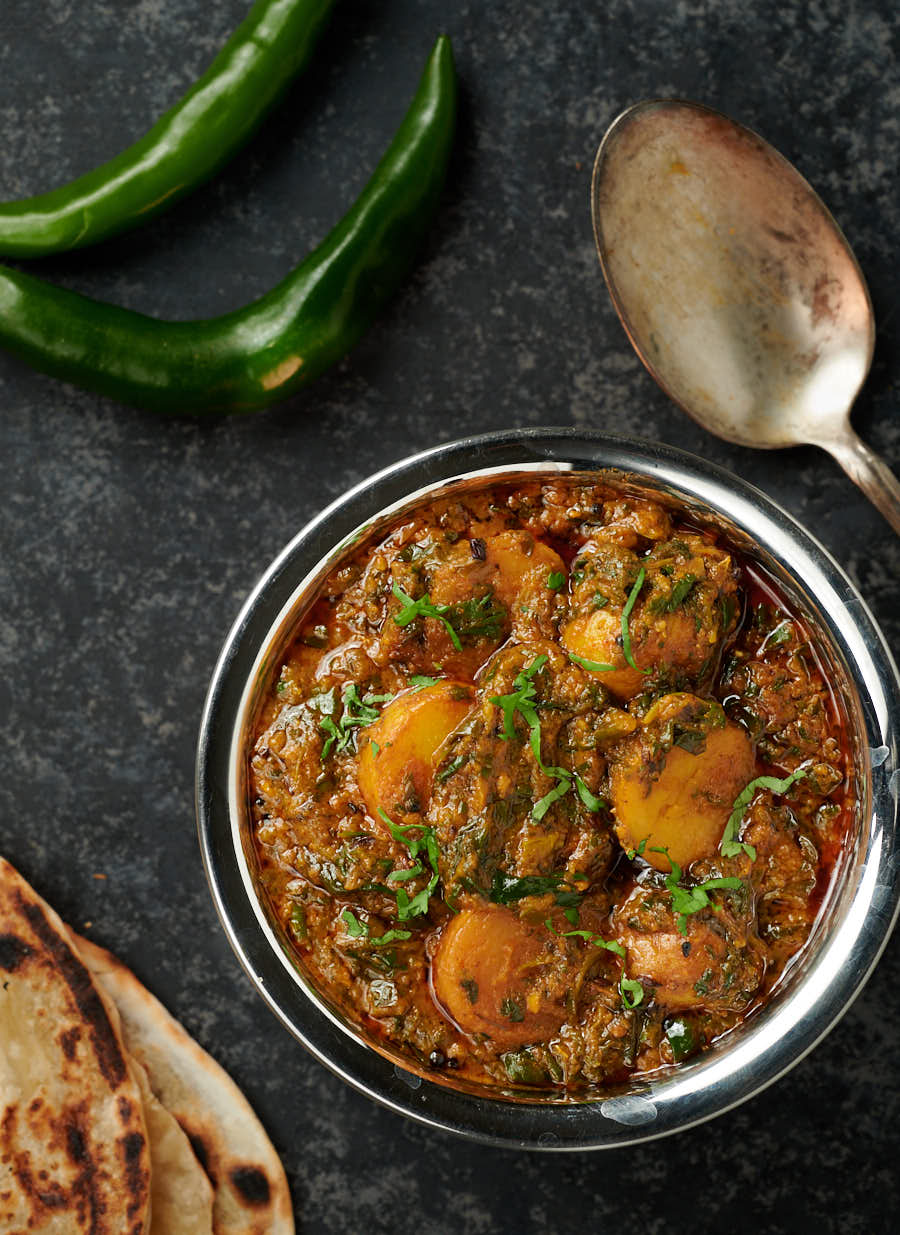 Saag aloo in a bowl with spoon from above.