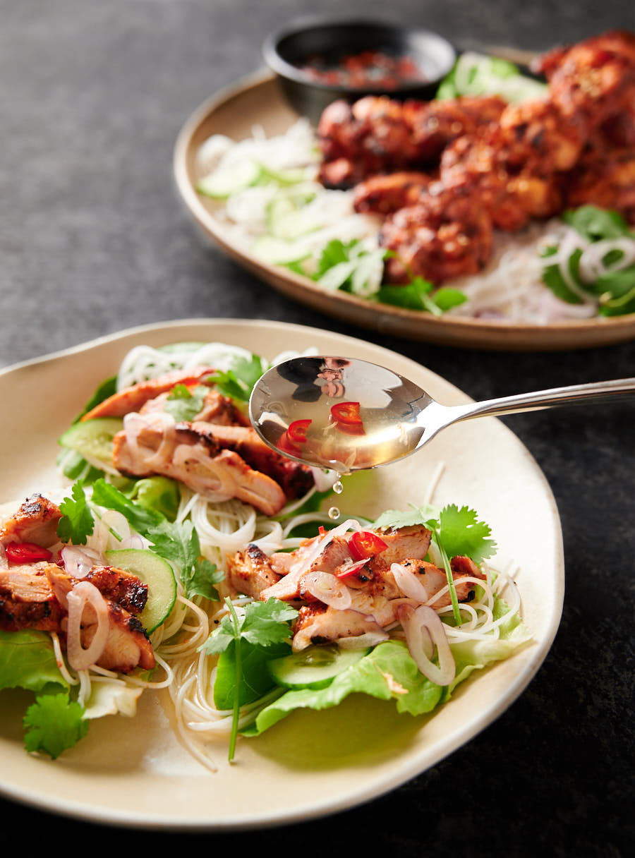Spoon drizzling nuoc cham overtop spicy Korean chicken lettuce wraps.