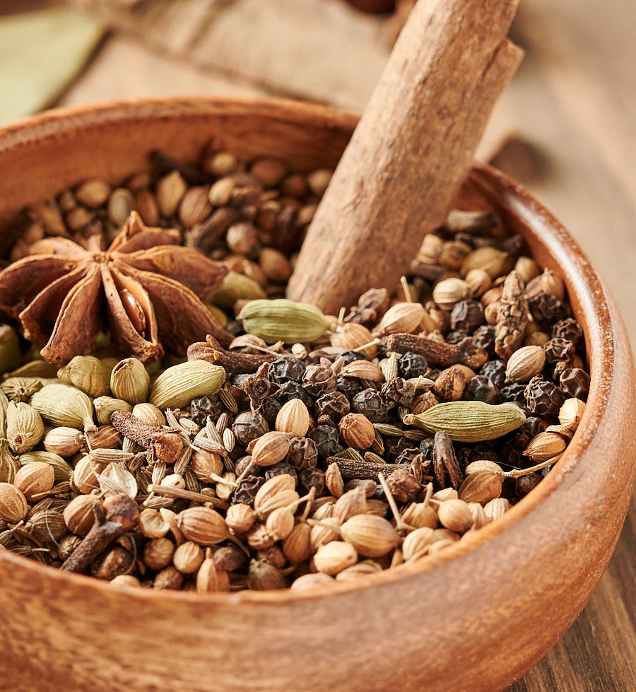 Garam Masala whole spices blend in a bowl with cinnamon bark stuck in it.