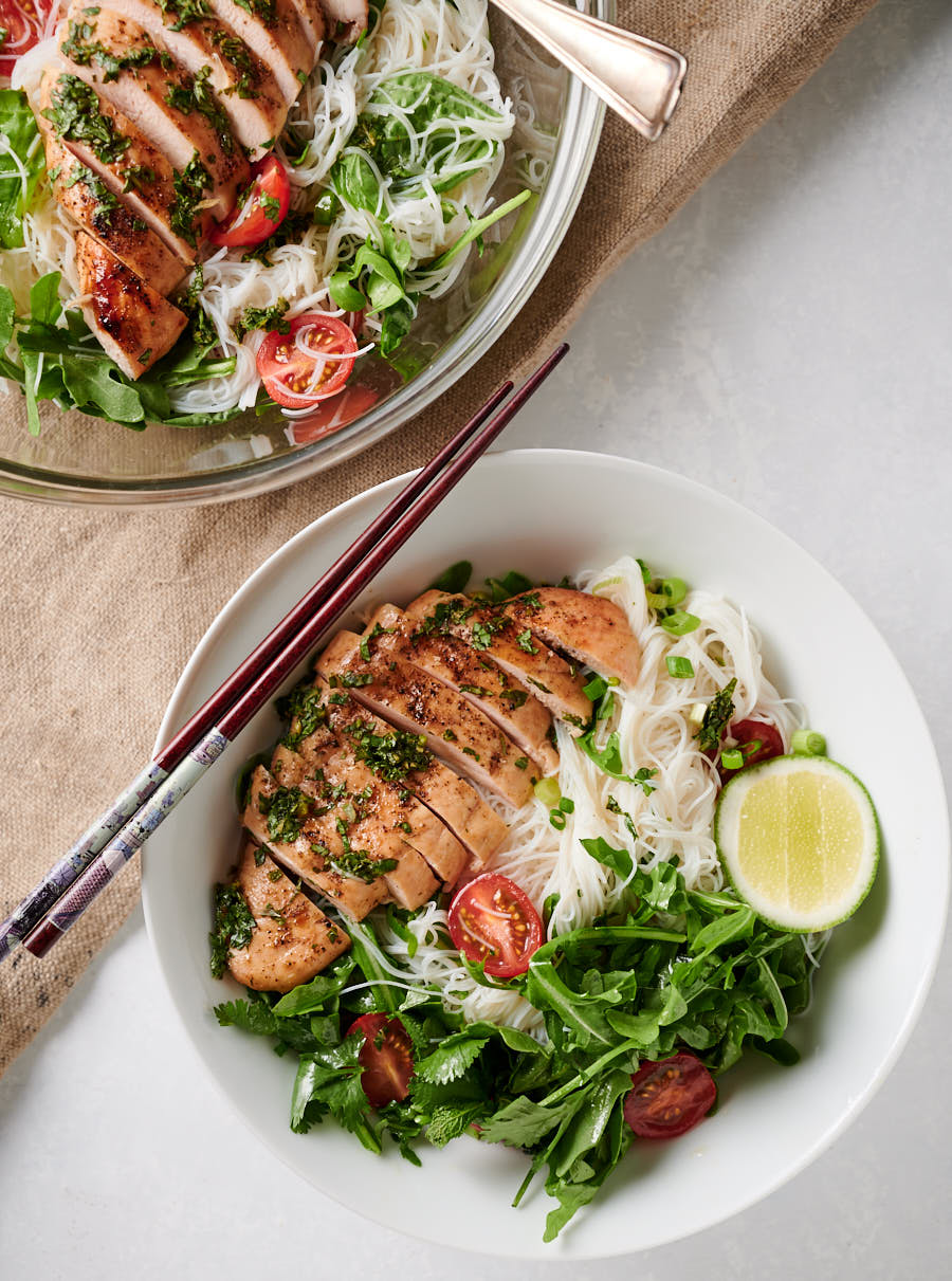 Thai chicken salad in a bowl along side more salad in a serving bowl.