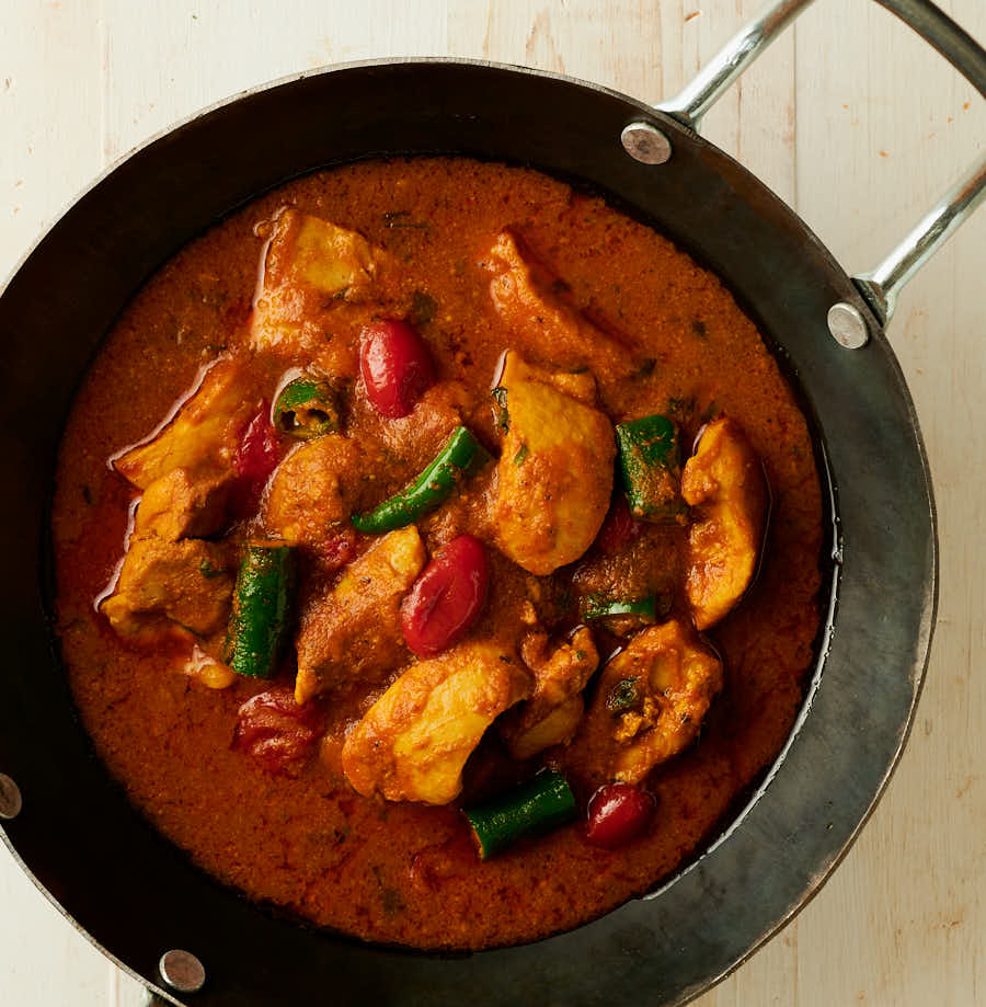 chicken masala curry in a black kadai from above