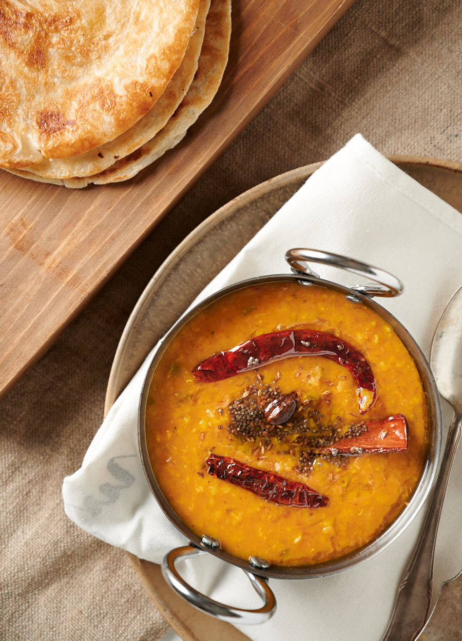 Dal tadka in a serving dish with parathas from above.