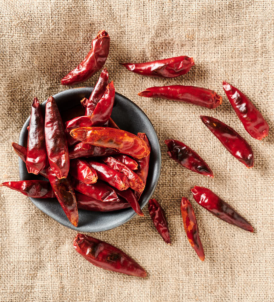 Red chilies spilling out of a bowl from above.