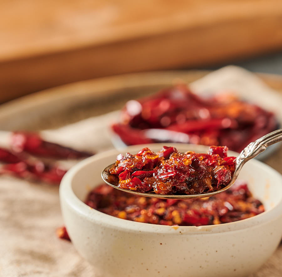 Spoonful of nam prik pao above a bowl of chili paste.