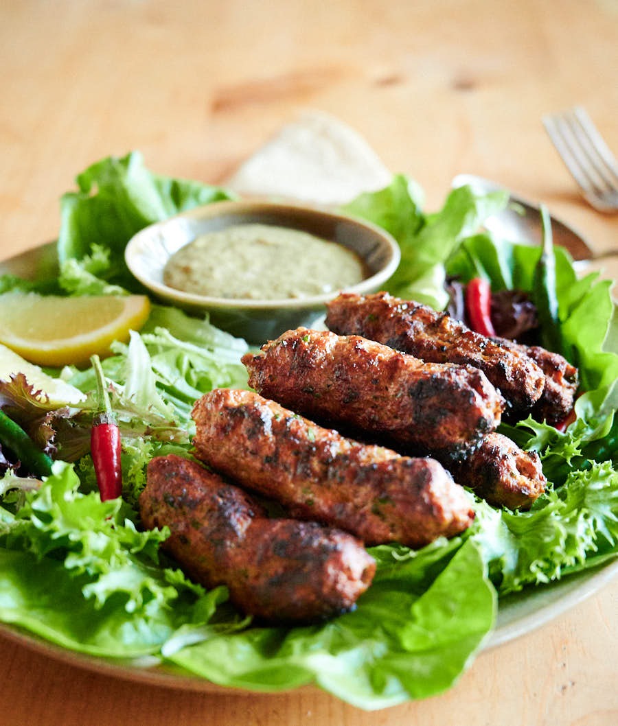 Indian seekh kebab on a plate with garnishes and dip from above.