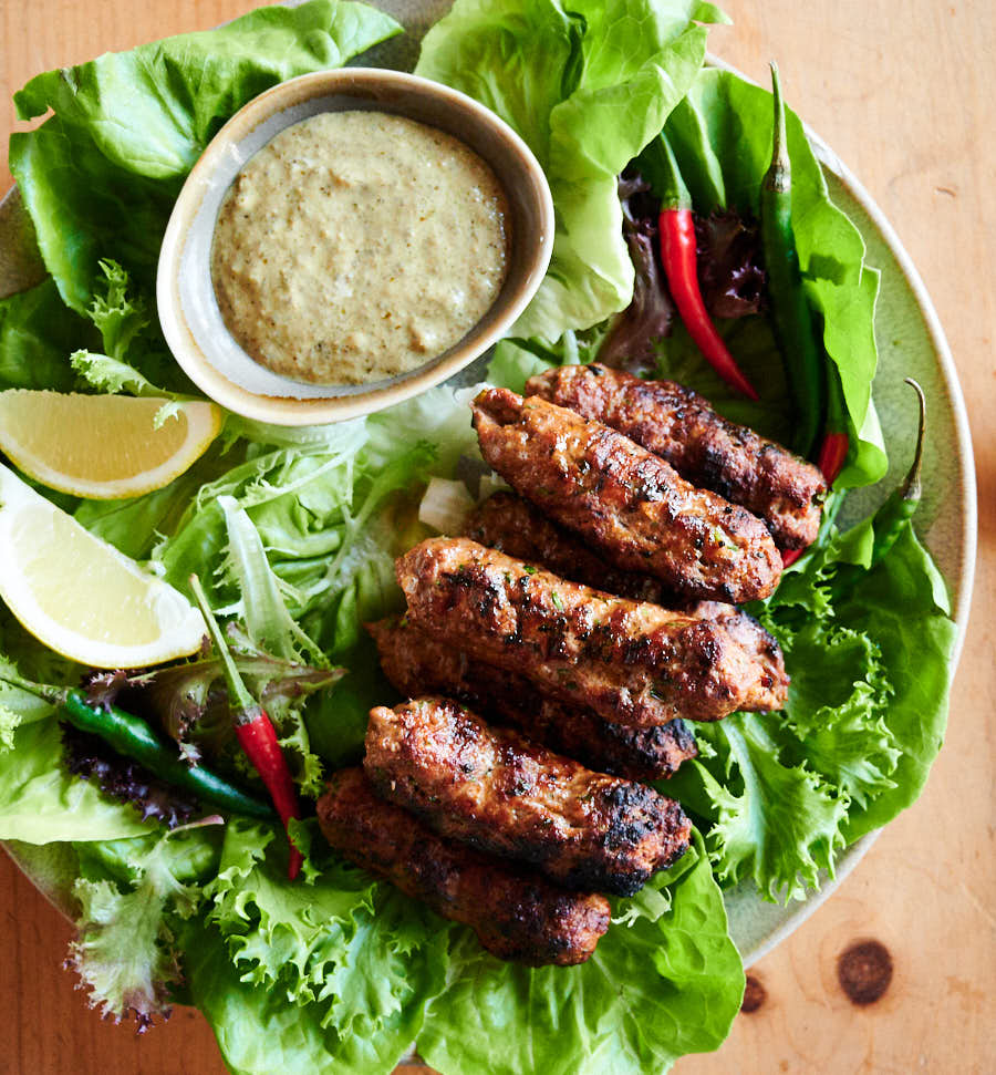 Indian seekh kebab on a plate with garnishes and dip from above.