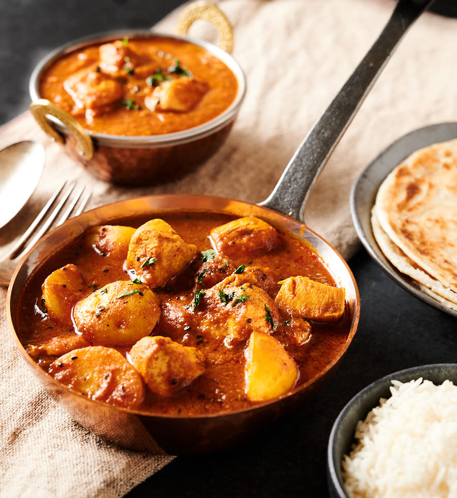 Bengali chicken curry with rice and parathas from the front.