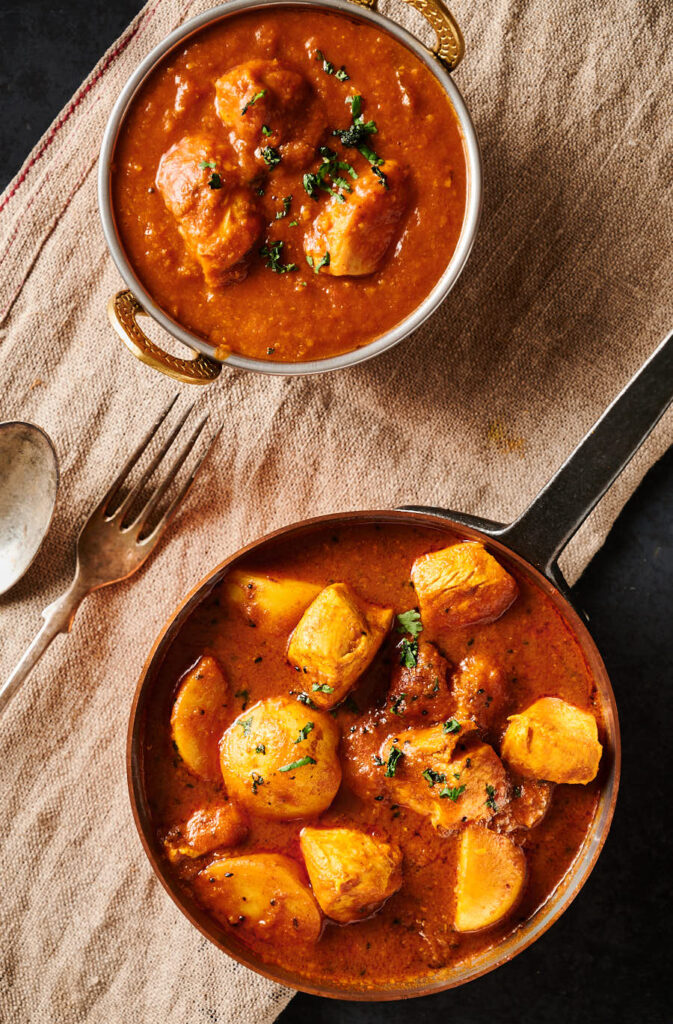 Bengali chicken curry in a copper pan from above.